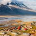 Vista panorâmica de Longyearbyen, Noruega, com casas coloridas, montanhas nevadas e rios congelados ao fundo.
