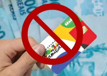 Cartão do Bolsa Família com a inscrição 'Programa Bolsa Família' ao fundo e notas de 100 reais, com um símbolo de proibição sobre o cartão, alertando sobre o erro que pode resultar na perda de benefícios.