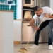 Homem varrendo a casa na cozinha com uma vassoura, em um momento de limpeza doméstica.