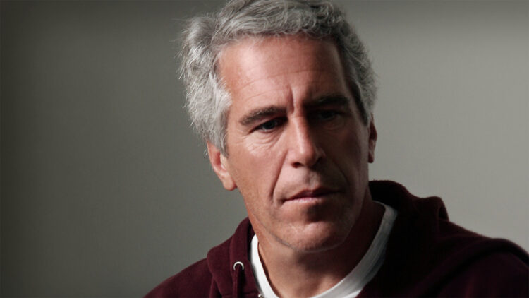 Caso Epstein: conheça os poderosos citados no novo vazamento 1 Financista Jeffrey Epstein, um homem de pele clara e cabelos grisalhos curtos, vestindo um moletom bordô sobre uma camiseta branca. Ele tem uma expressão séria e olha levemente para o lado. O fundo é cinza neutro e desfocado.