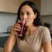 Mulher bebendo suco vermelho em um copo de vidro na cozinha