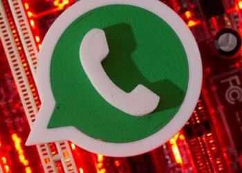 Ícone 3D do WhatsApp em verde e branco posicionado sobre uma placa de circuito eletrônico iluminada por luzes vermelhas intensas.