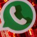 Ícone 3D do WhatsApp em verde e branco posicionado sobre uma placa de circuito eletrônico iluminada por luzes vermelhas intensas.