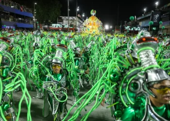 Integrantes desfilam com fantasias verdes e prateadas repletas de tubos luminosos na avenida