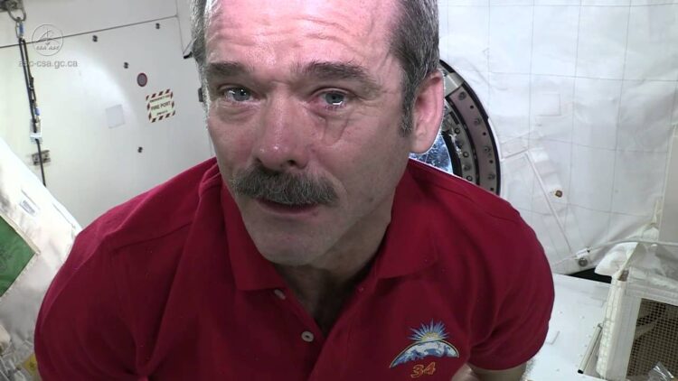 Astronauta de bigode com lágrima escorrendo dentro de estação espacial internacional