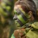 Militar brasileira com pintura camuflada no rosto durante atividade de instrução, representando a seleção feminina para o serviço militar.