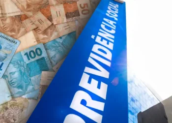 Notas de real espalhadas ao lado de placa azul escrita "Previdência Social"