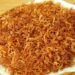 Revelado: O segredo da cebola crocante de hamburgueria 12 Pilha de anéis de cebola bem finos e fritos até atingirem um tom dourado intenso, repousando sobre uma folha de papel toalha branco. As rodelas exibem uma textura leve e sequinha, típica do empanamento com amido de milho.