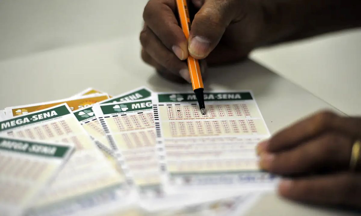 Quer ganhar R$ 145 milhões? Mega-Sena acumula e mostra como fazer sua aposta 2 Pessoa preenche volante da Mega-Sena com caneta, ilustrando dicas para apostar de forma consciente.