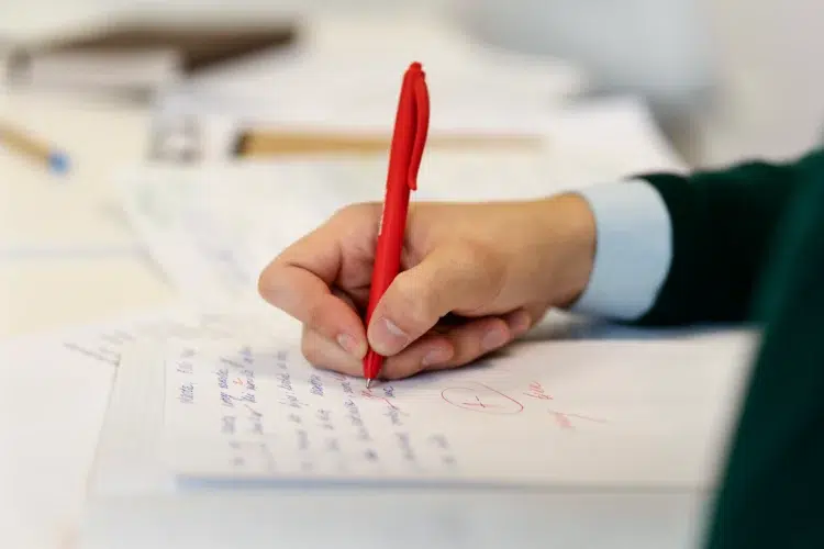 O que a sua letra diz sobre você? A ciência explica o que o formato da escrita revela sobre a mente 1 Mão segurando caneta vermelha escrevendo texto em folha branca