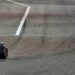 Visão ampla de dois carros de Fórmula 1, um da Ferrari e outro da McLaren, acelerando na reta principal do circuito de Sakhir durante os testes de pré-temporada.