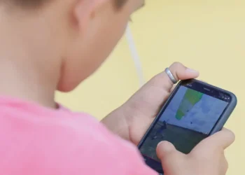 Criança segurando smartphone jogando jogo com cenário ao ar livre