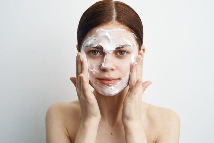 O segredo do "Pó de Arroz": O truque asiático que clareia manchas na pele sem usar ácidos 1 Mulher espalha máscara cremosa de pó de arroz no rosto usando as mãos frente a fundo claro