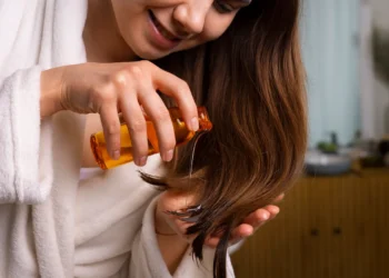 Mulher aplicando óleo natural no cabelo e riscos escondidos.