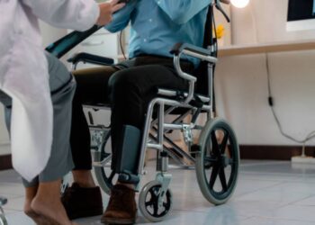 Paciente em cadeira de rodas durante atendimento clínico, representando estudos sobre recuperação de movimentos em pessoas tetraplégicas.