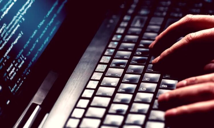 Pessoa digitando em teclado com códigos na tela, representando oportunidades de formação em cibersegurança pelo programa Hackers do Bem.