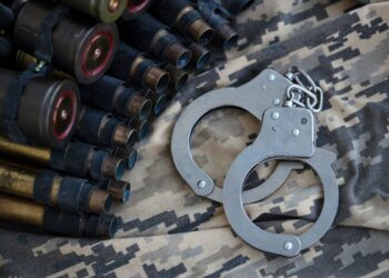 Algemas sobre uniforme tático ao lado de munições, representando endurecimento das leis para crimes contra agentes de segurança.