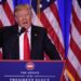 O Presidente Donald Trump em um púlpito com o selo presidencial, falando ao microfone com várias bandeiras dos Estados Unidos ao fundo.