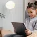 Menina sentada em poltrona utilizando tablet com expressão concentrada