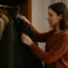 Mulher segurando uma jaqueta preta em frente ao guarda-roupa