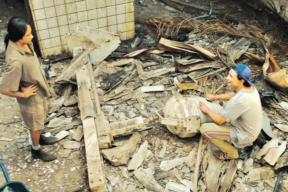 Série "Emergência Radioativa": Produção nacional ganha destaque internacional 2 Dois homens interagem próximos a máquina em meio a entulhos e destroços