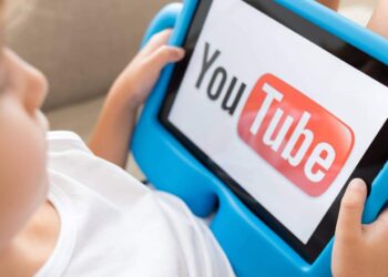 Criança segurando tablet com logo do YouTube exibido na tela enquanto assiste vídeos