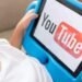 Criança segurando tablet com logo do YouTube exibido na tela enquanto assiste vídeos