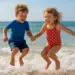 Duas crianças pulando na praia, sorrindo e segurando as mãos