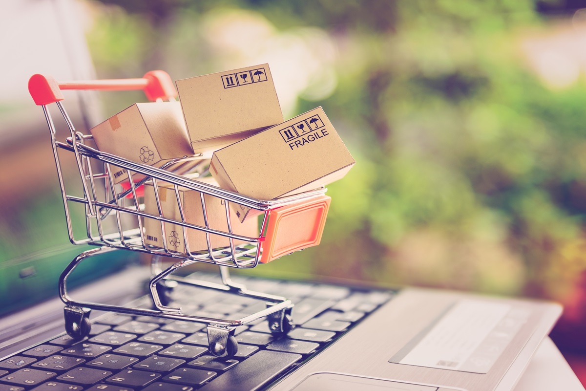 Dia do Consumidor: saiba como não cair em golpes e garantir grandes ofertas e promoções 2 Carrinho de compras cheio de caixas sobre teclado de notebook representando e-commerce