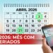 Calendário de abril de 2026 com feriados destacados e celular mostrando notificações de feriados