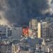 Prédios altos próximos a incêndio intenso com fumaça densa subindo no céu.