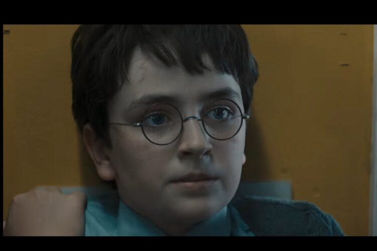 Harry Potter usando óculos redondos encara algo em ambiente iluminado
