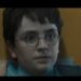 Harry Potter usando óculos redondos encara algo em ambiente iluminado