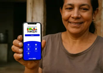 Mulher sorridente exibindo celular com tela do Bolsa Família em ambiente simples