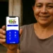 Mulher sorridente exibindo celular com tela do Bolsa Família em ambiente simples