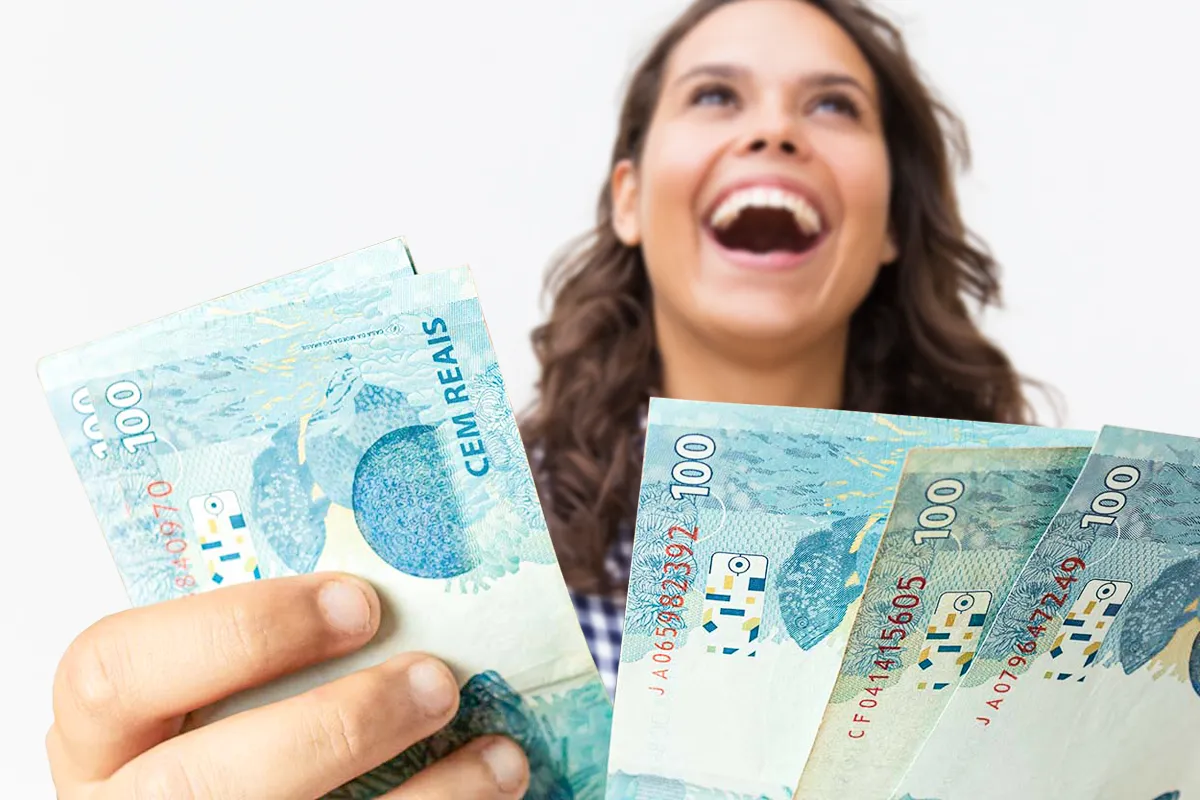 Projeto sugere salário mínimo de R$ 2.750 para trabalhadores do comércio 2 Mulher segurando diversas cédulas de R$ 100 com expressão de alegria em fundo claro.