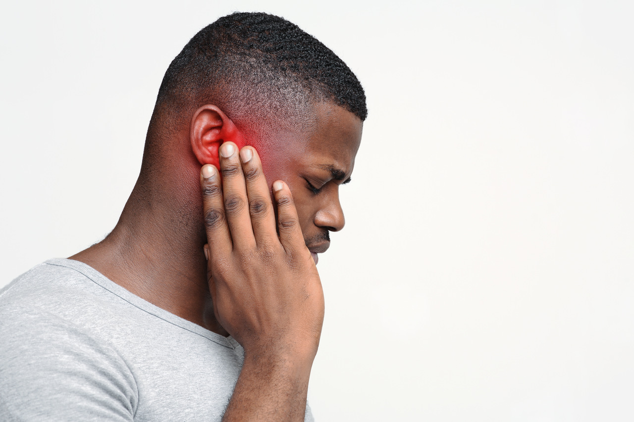 Por que você nunca deve ignorar um "apito" no ouvido quando está em silêncio 2 Homem com expressão de dor tocando a orelha vermelha com a mão direita