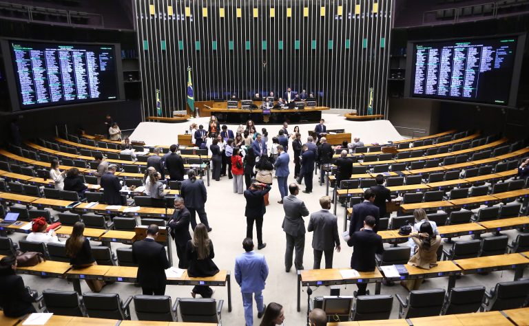 Mulheres poderão comprar spray de pimenta para proteção pessoal após aprovação da Câmara 2 Visão panorâmica do Plenário da Câmara dos Deputados em Brasília, mostrando parlamentares circulando e conversando entre as bancadas durante uma sessão de votação.