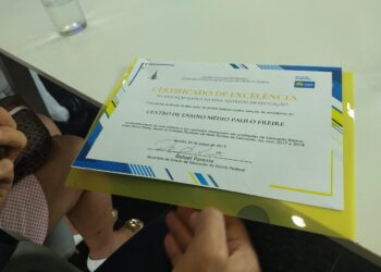 Documento de certificação escolar sendo segurado por uma pessoa, representando a conclusão do ensino médio por meio de sistema digital.