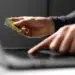 Pessoa digita no notebook segurando cartão de crédito dourado