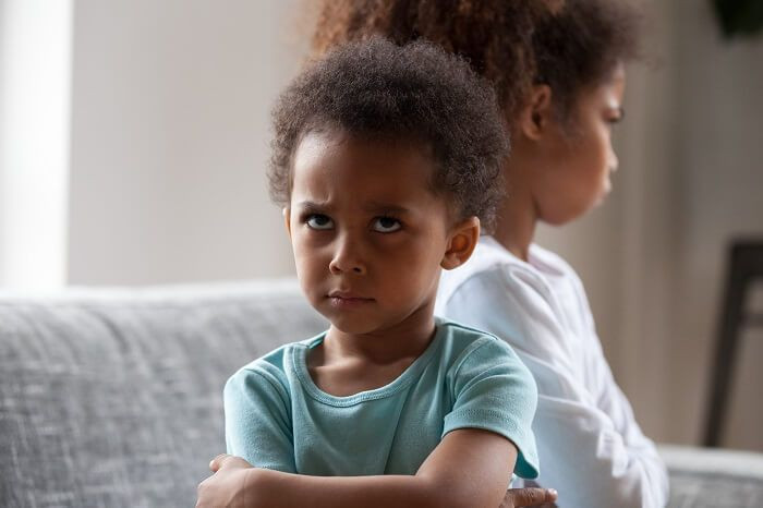 O "efeito dopamina" nos vídeos curtos: Por que seu filho fica irritado quando você tira o celular 2 Menina com expressão irritada sentada de braços cruzados em sofá claro
