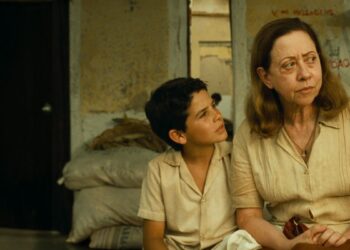 A atriz Fernanda Montenegro e o ator Vinícius de Oliveira sentados em um cenário do filme Central do Brasil.