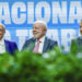 Fim da escala 6x1: Governo Lula defende nova fórmula de negociação com patrões e empregados 13 Três homens de terno sorrindo sentados à mesa com painel azul ao fundo