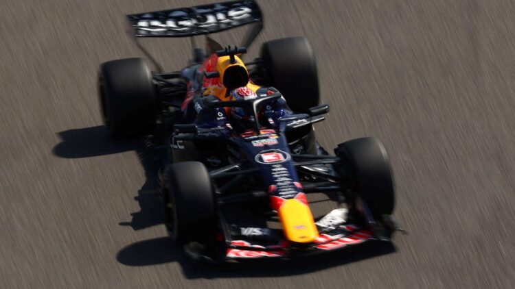 Guerra no Oriente Médio pode mudar o calendário da Fórmula 1; saiba o que está em jogo 1 Visão aérea em ângulo oblíquo de um carro de Fórmula 1 da Red Bull Racing, com detalhes em azul marinho e bico amarelo, acelerando em uma pista cinza sob luz solar intensa.