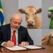 Homem assinando documento com bandeira do Brasil e imagens de animais ao fundo