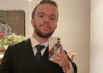 Advogado com nanismo tira selfie de terno em ambiente residencial bem iluminado