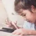 Menina deitada interagindo com tablet preto enquanto desliza o dedo na tela