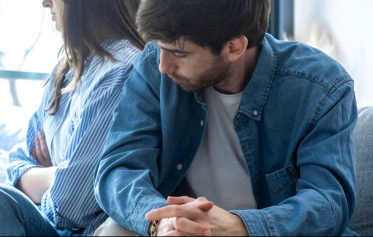 Relacionamento desgastado? Veja formas de reconstruir a conexão do casal 1 Casal sentado após discussão em casa, representando desgaste no relacionamento e distanciamento emocional