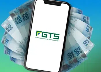 Smartphone exibe logo do FGTS sobre leque de notas de 100 reais em fundo azul esverdeado