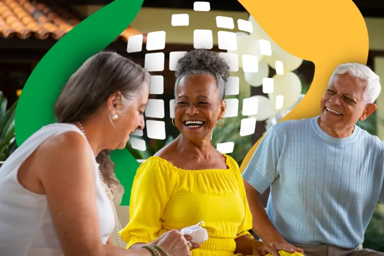 Três idosos sorridentes em ambiente externo: mulher de branco, mulher de amarelo com brincos e homem de blusa cinza